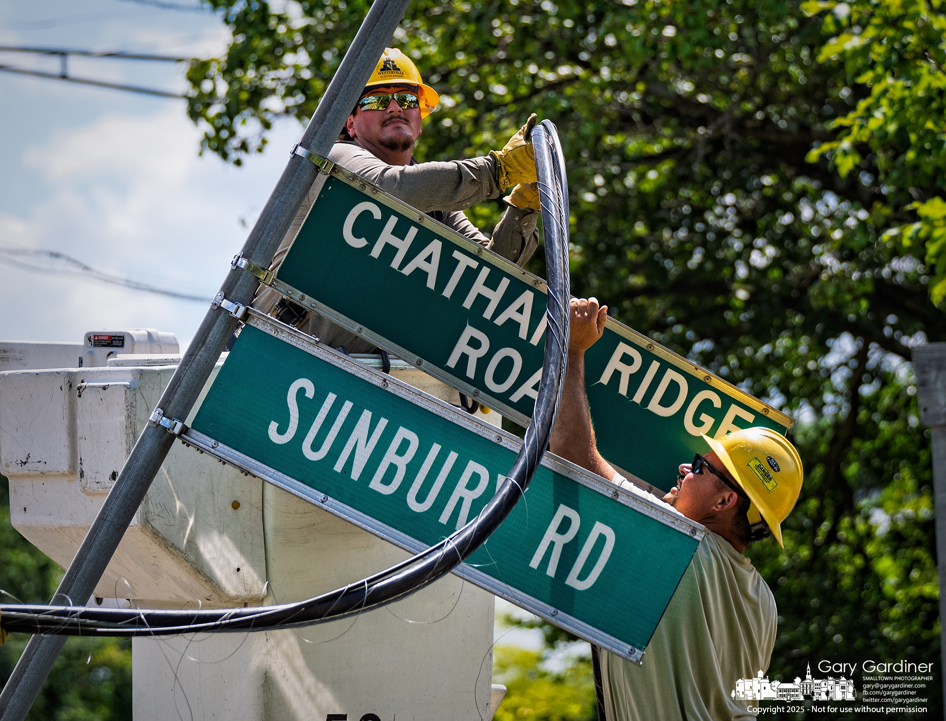 Workers guide the cable around the bent street signs.