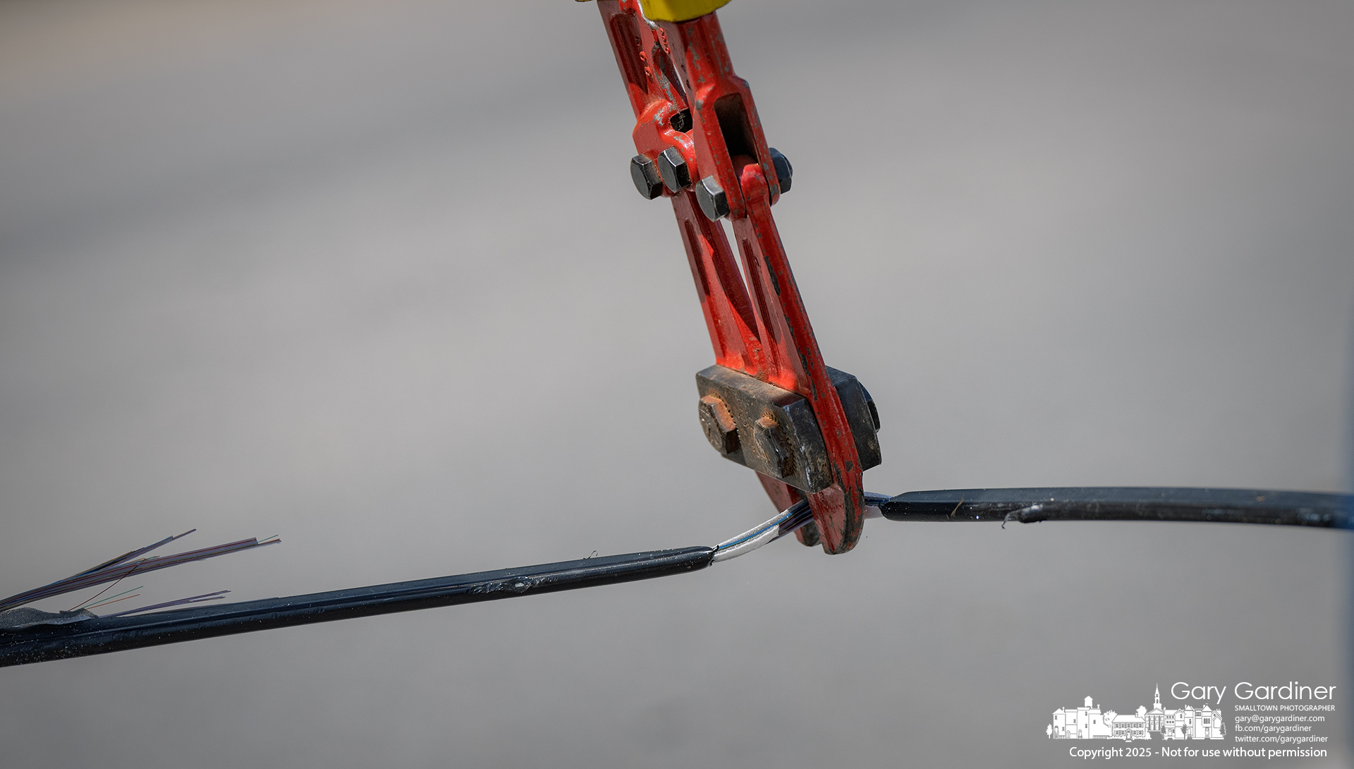 Bolt cutters snip the fiber optic lash cable.